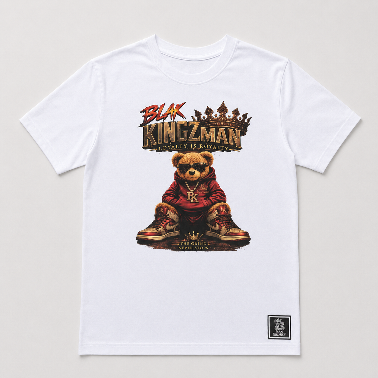 BLAK KINGZMAN Grind Bear White Tee — seated bear mascot in red hoodie and gold Jordans, The Grind Never Stops