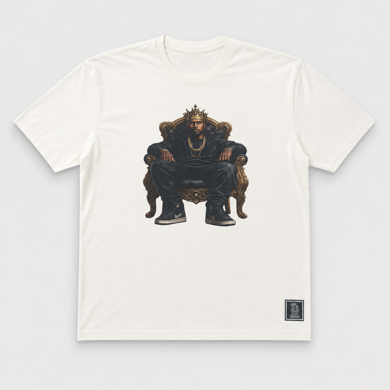BLAK KINGZMAN King on Throne White Tee — illustrated crowned Black man seated on an ornate gold throne on cream unisex tee
